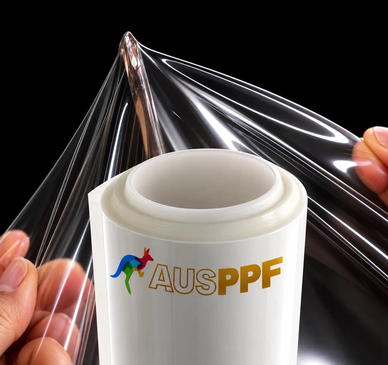 A sheet of AusPPF Clear 7.5 paint protection film held up by hand, showing its optical clarity against a roll printed with the AusPPF logo.