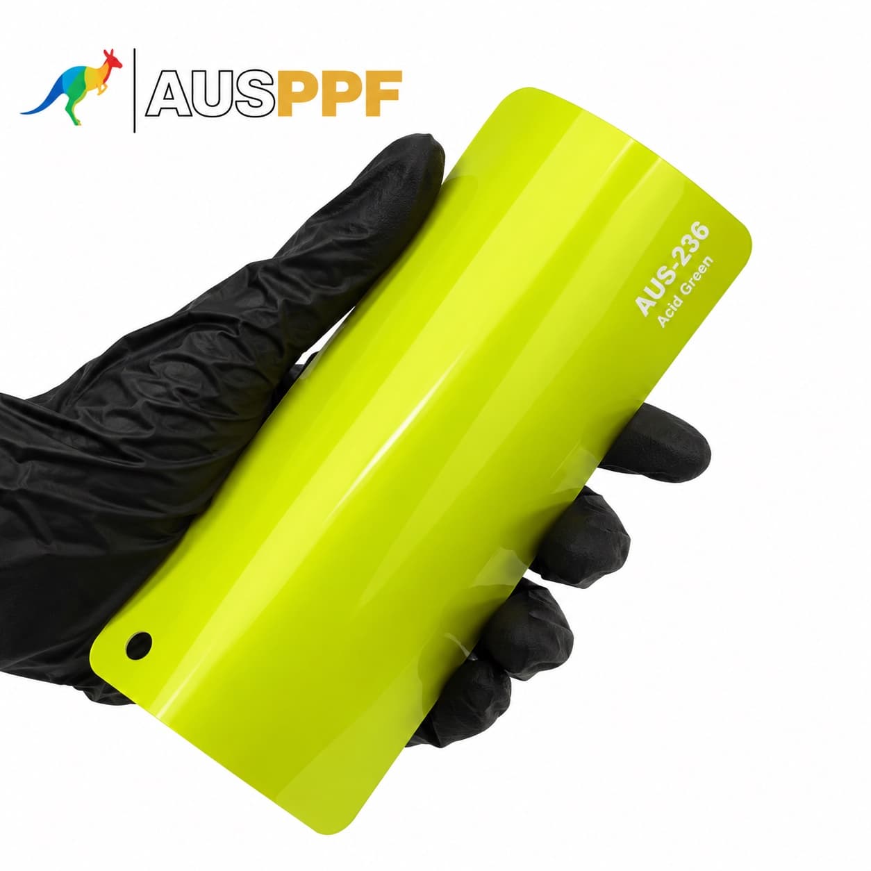 A gloved hand holding a swatch of AusPPF AUS-236 Acid Green PPF, showing its gloss finish.