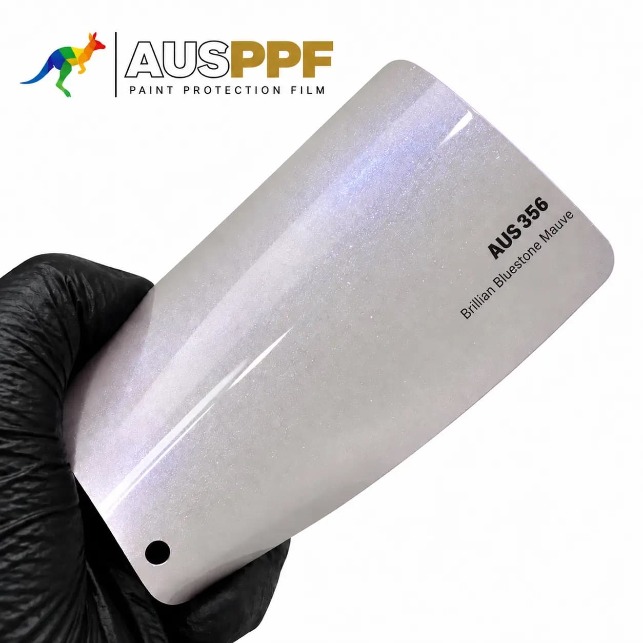 A gloved hand holding a swatch of AusPPF AUS-356 Brilliant Bluestone Mauve PPF, showing its gloss finish.