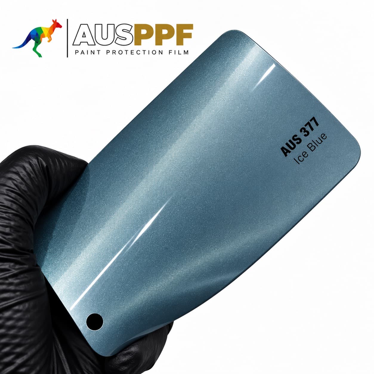 A gloved hand holding a swatch of AusPPF AUS-377 Ice Blue PPF, showing its gloss finish.