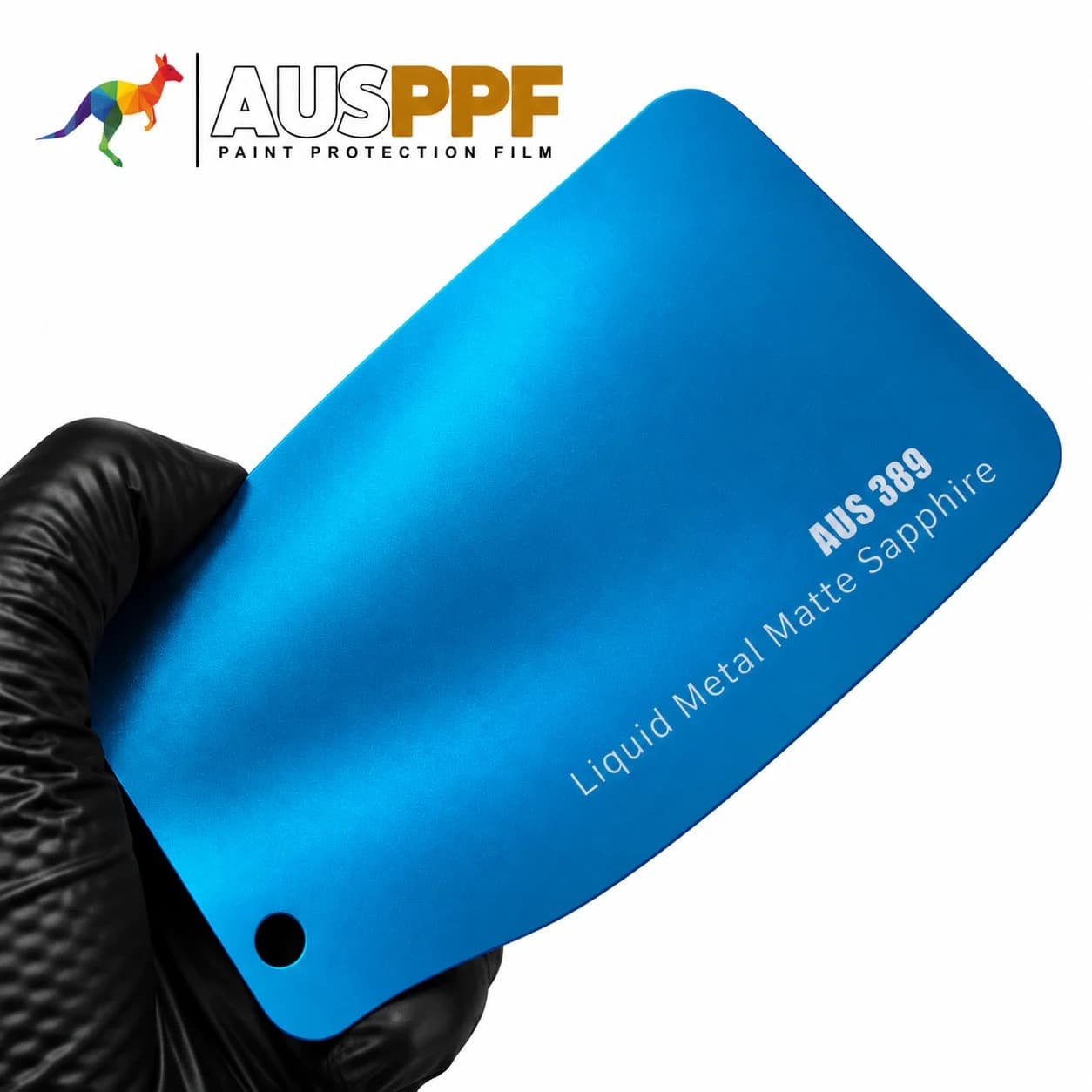 A gloved hand holding a swatch of AusPPF AUS-389 Liquid Metal Matte Sapphire PPF, showing its matte finish.