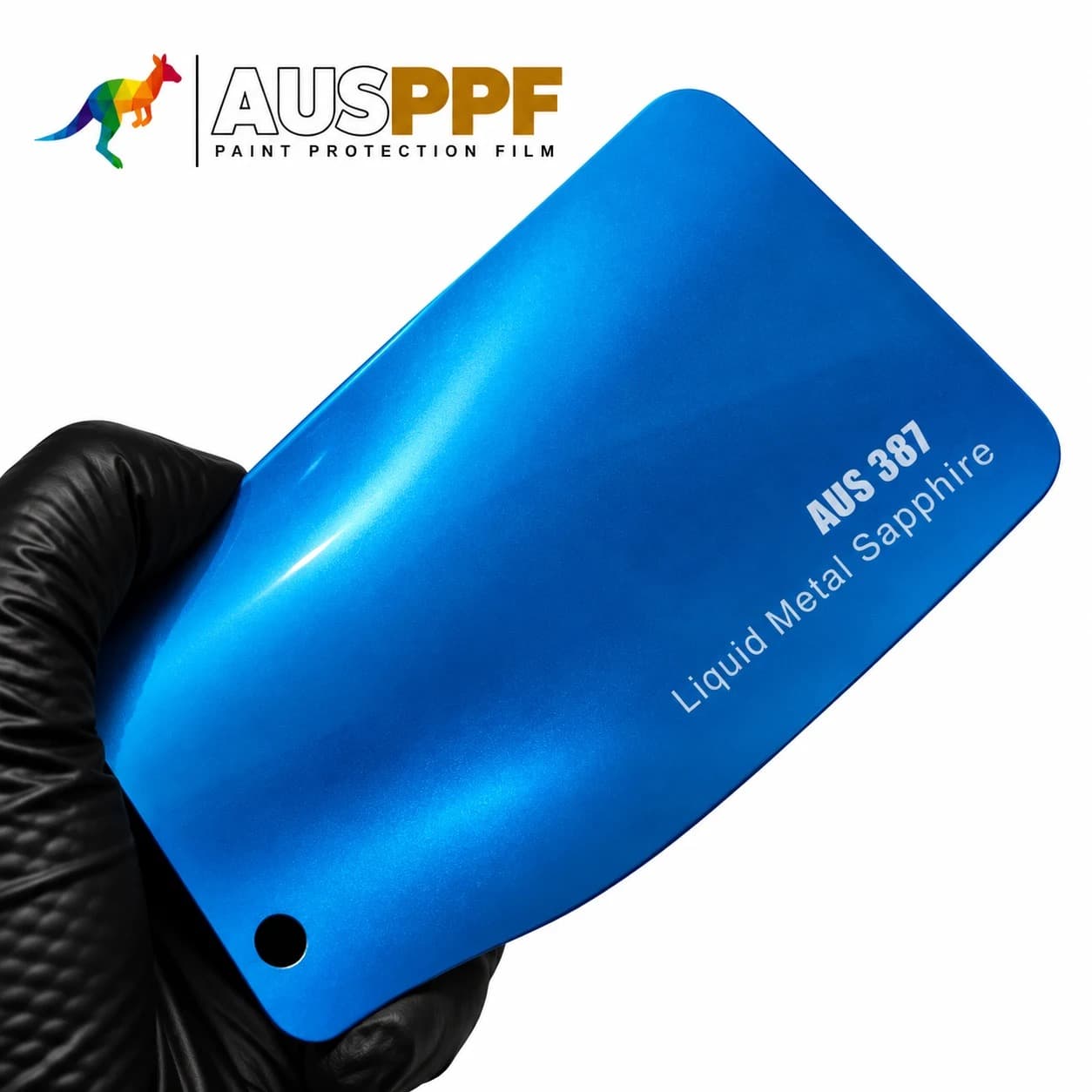 A gloved hand holding a swatch of AusPPF AUS-387 Liquid Metal Sapphire PPF, showing its gloss finish.