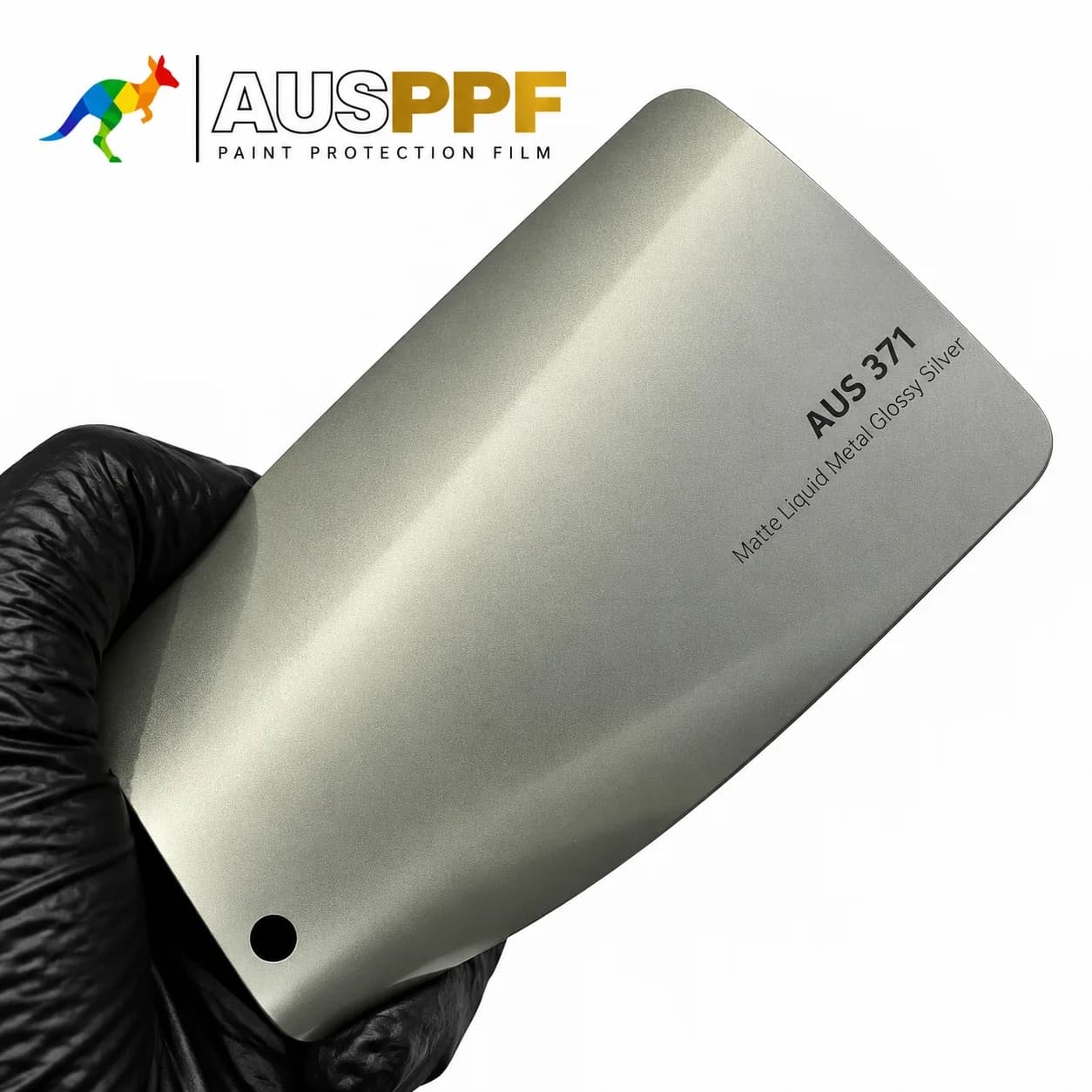 A gloved hand holding a swatch of AusPPF AUS-371 Matte Liquid Metal Glossy Silver PPF, showing its matte finish.