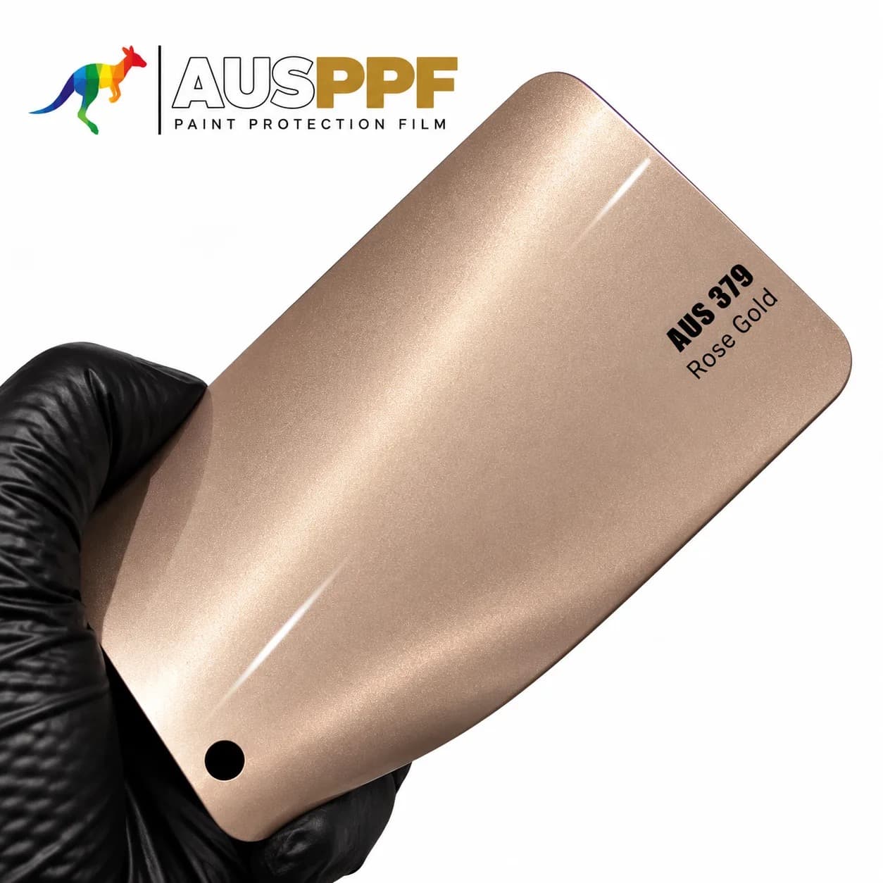 A gloved hand holding a swatch of AusPPF AUS-379 Rose Gold PPF, showing its gloss finish.