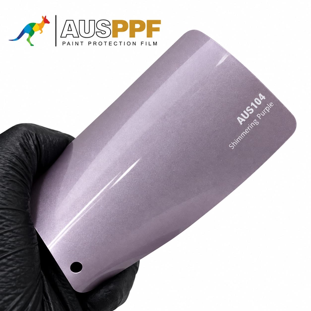 A gloved hand holding a swatch of AusPPF AUS-104 Shimmering Purple PPF, showing its gloss finish.